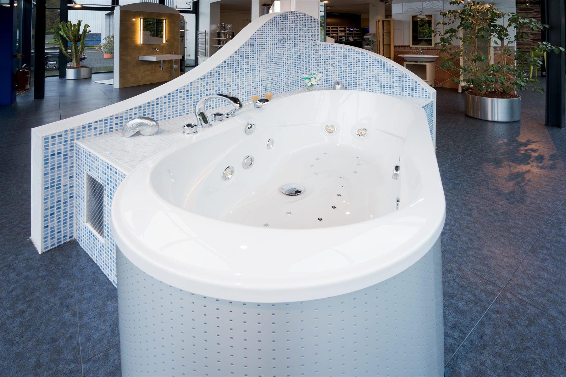 Whirlpool-Eckbadewanne mit blau gefliester Mosaikverkleidung in der Christoffel-Ausstellung